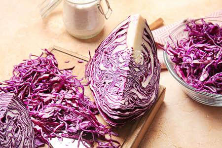 Board with cut fresh purple cabbage on color background, closeup