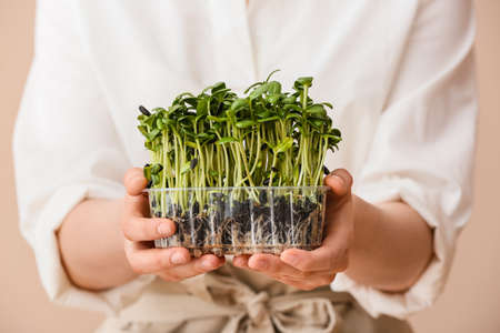 Woman with fresh micro green on color background