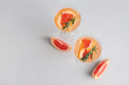 Glasses of tasty grapefruit cocktail with rosemary on gray background
