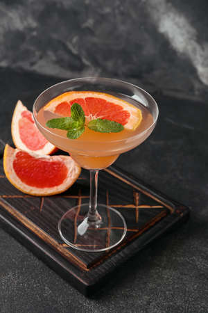 Glass of tasty grapefruit cocktail on dark backgroundの写真素材