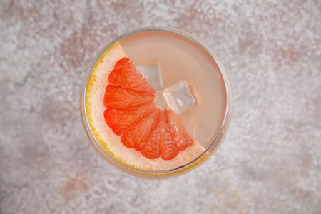 Glass of tasty grapefruit cocktail on gray backgroundの写真素材