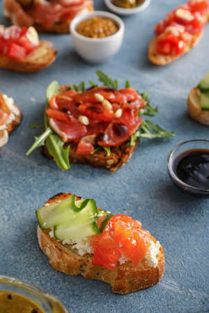 Different tasty bruschettas and ingredients on color backgroundの写真素材