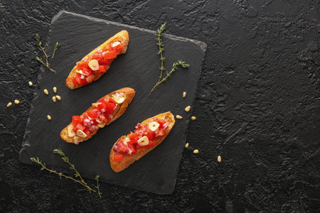 Tasty bruschettas with tomatoes on dark background