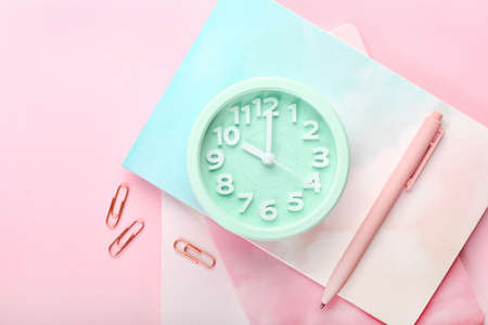 Stylish alarm clock and stationery on color background