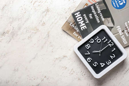Stylish clock and magazines on grunge background