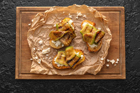 Tasty bruschettas with cheese and grilled zucchini on dark backgroundの写真素材