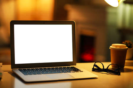 Modern laptop, glasses and coffee on table in the evening
