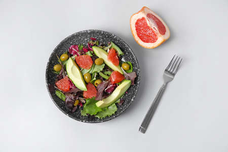 Plate with tasty grapefruit salad on white background