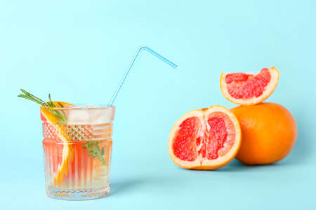 Glass of tasty grapefruit lemonade on color background