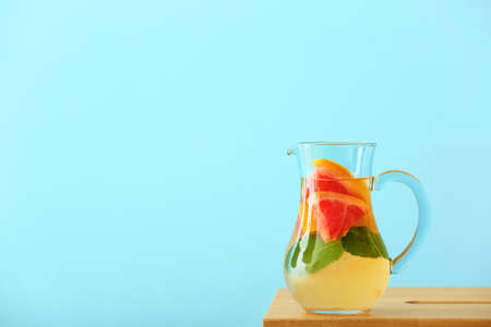 Jug of tasty grapefruit lemonade on table against color backgroundの写真素材