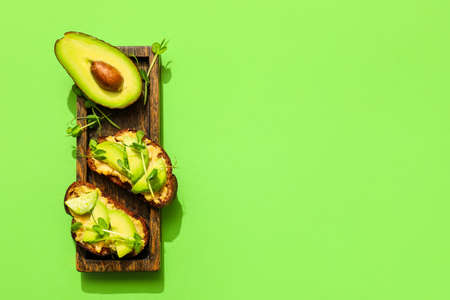 Tasty bruschettas with avocado and hummus on color background