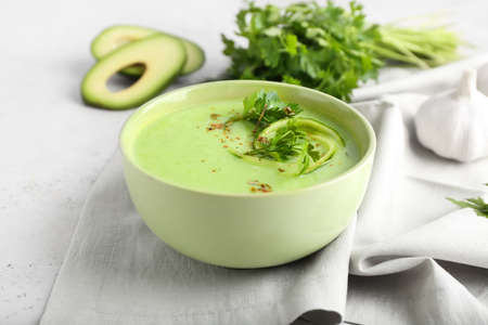 Bowl with green gazpacho, avocado and parsley on light backgroundの写真素材