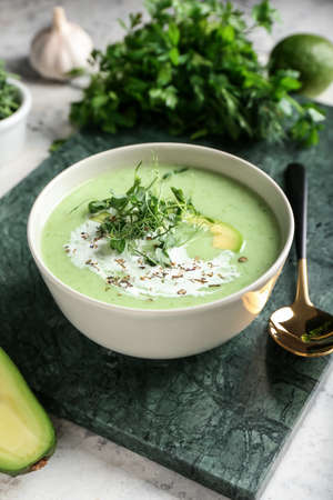 Bowl with green gazpacho and ingredients on grunge backgroundの写真素材