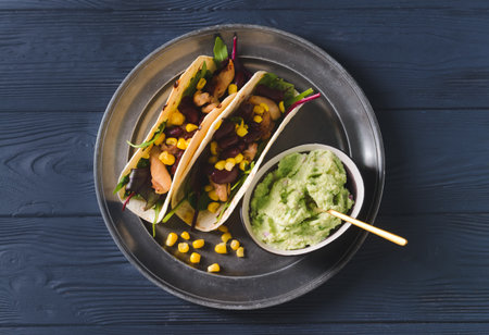 Plate with tacos and tasty guacamole in bowl on dark wooden backgroundの写真素材