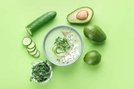 Bowl with green gazpacho and ingredients on color backgroundの写真素材