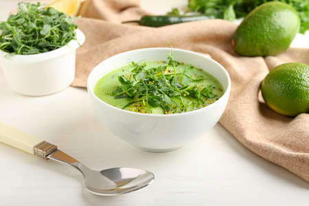 Bowl with green gazpacho and ingredients on light backgroundの写真素材