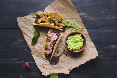 Composition with tacos and tasty guacamole in bowl on dark wooden backgroundの写真素材