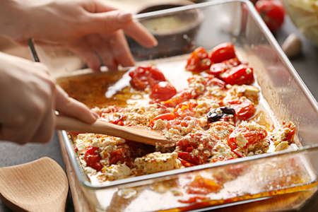Woman preparing tomatoes and feta cheese in the kitchen