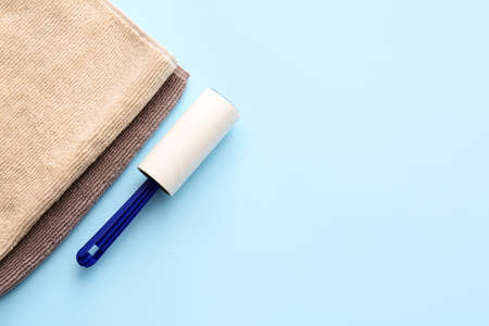 Lint roller with towels on color background
