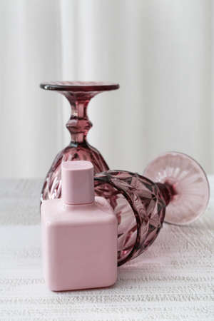 Perfume bottle and stylish glasses on white table