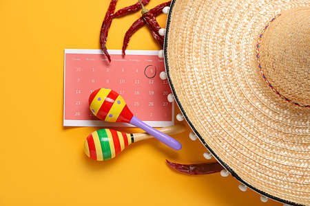 Mexican maracas, calendar with marked date 5 May (Cinco de Mayo) and sombrero on color background