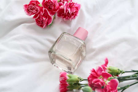 Perfume and beautiful carnation flowers on white background