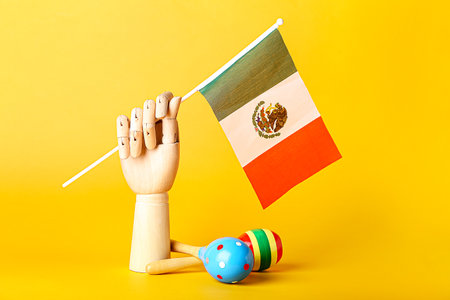 Wooden hand with Mexican flag and maracas on color backgroundの写真素材