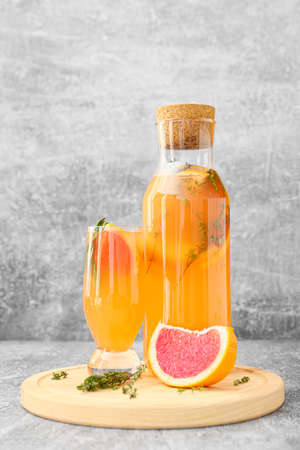 Glass and bottle of tasty grapefruit lemonade on gray backgroundの写真素材