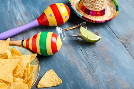 Mexican maracas, nachos, tequila and sombrero on wooden background