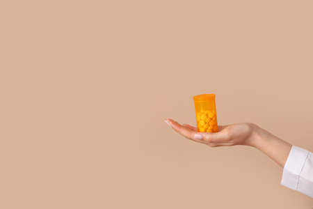 Female doctor holding bottle with pills on color backgroundの写真素材