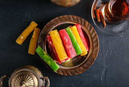 Plate with tasty Turkish delight on dark background