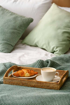 Tray with cup of coffee and croissant on bedの写真素材