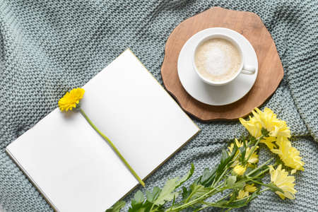 Cup pf coffee with book and flowers on knitted plaidの写真素材