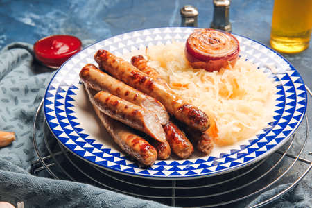 Plate with tasty grilled sausages and sauerkraut on color background, closeupの写真素材