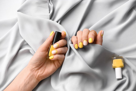 Female hands with beautiful manicure, nail polishes and fabric, closeupの写真素材