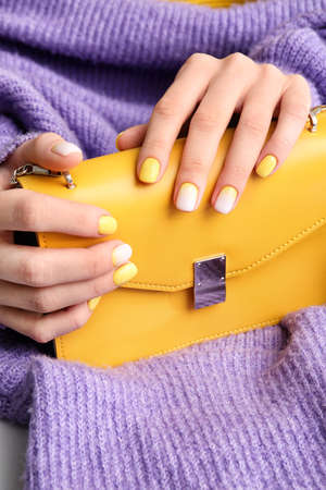 Female hands with beautiful manicure and bag on color fabric background, closeupの写真素材