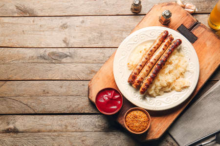 Plate with tasty grilled sausages, sauerkraut and sauces on wooden backgroundの写真素材