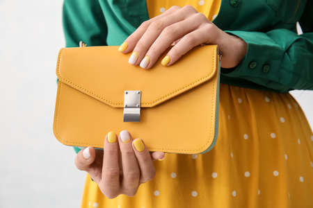 Woman with beautiful manicure holding bag on white background, closeup