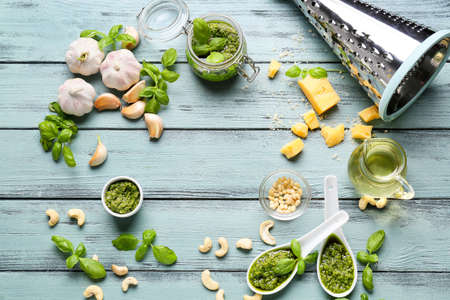 Frame made of pesto sauce and ingredients on color wooden background
