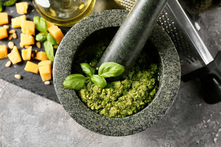 Mortar and pestle with fresh pesto sauce on grunge background, closeupの写真素材