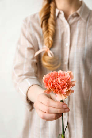 Young woman with beautiful carnation flower on white background, closeupの写真素材
