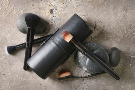 Set of makeup brushes with case and spa stones on grunge background