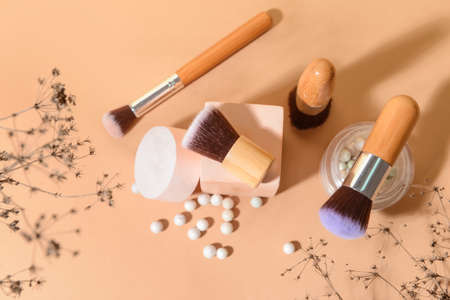 Makeup brushes with powder and decor on color background