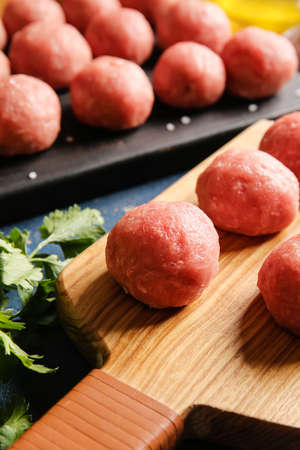 Wooden boards with raw cutlets made of fresh forcemeat on color background