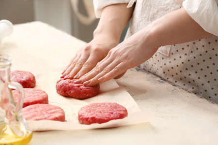 Woman preparing tasty cutlets made of fresh forcemeat at table in kitchen, closeupの写真素材