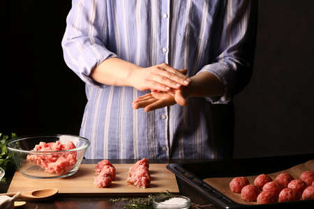 Woman preparing tasty cutlets made of fresh forcemeat on dark background, closeupの写真素材