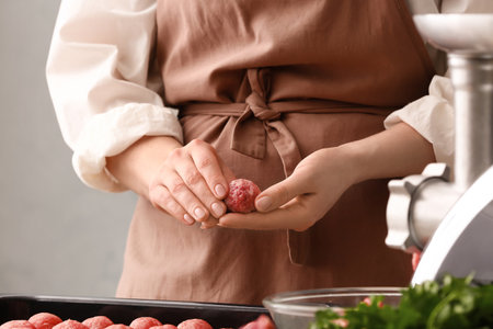 Woman preparing tasty cutlets made of fresh forcemeat at table in kitchen, closeupの写真素材