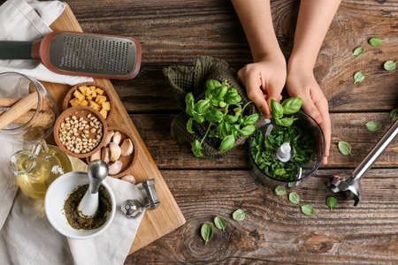 Woman preparing tasty pesto sauce on wooden backgroundの写真素材