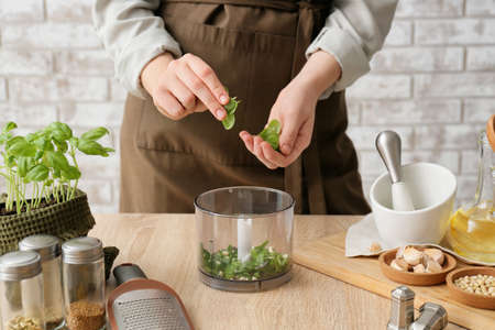 Woman preparing tasty pesto sauce on table