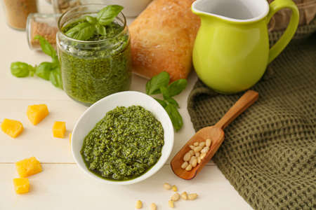 Bowl with tasty pesto sauce, cheese and pine nuts on light wooden backgroundの写真素材